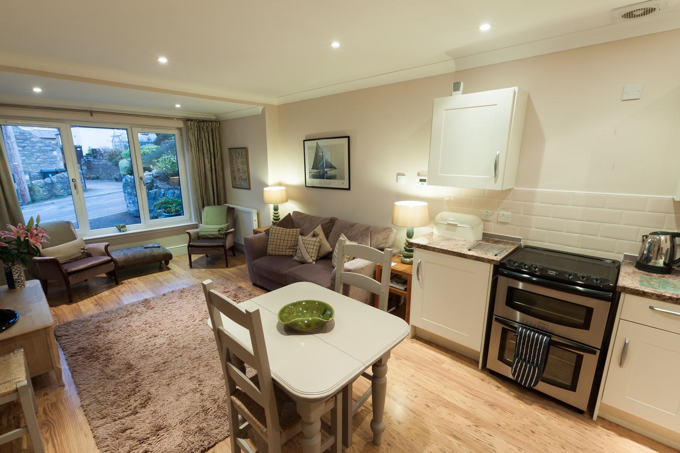 Open plan kitchen/ living/ dining room with large window looking onto driveway