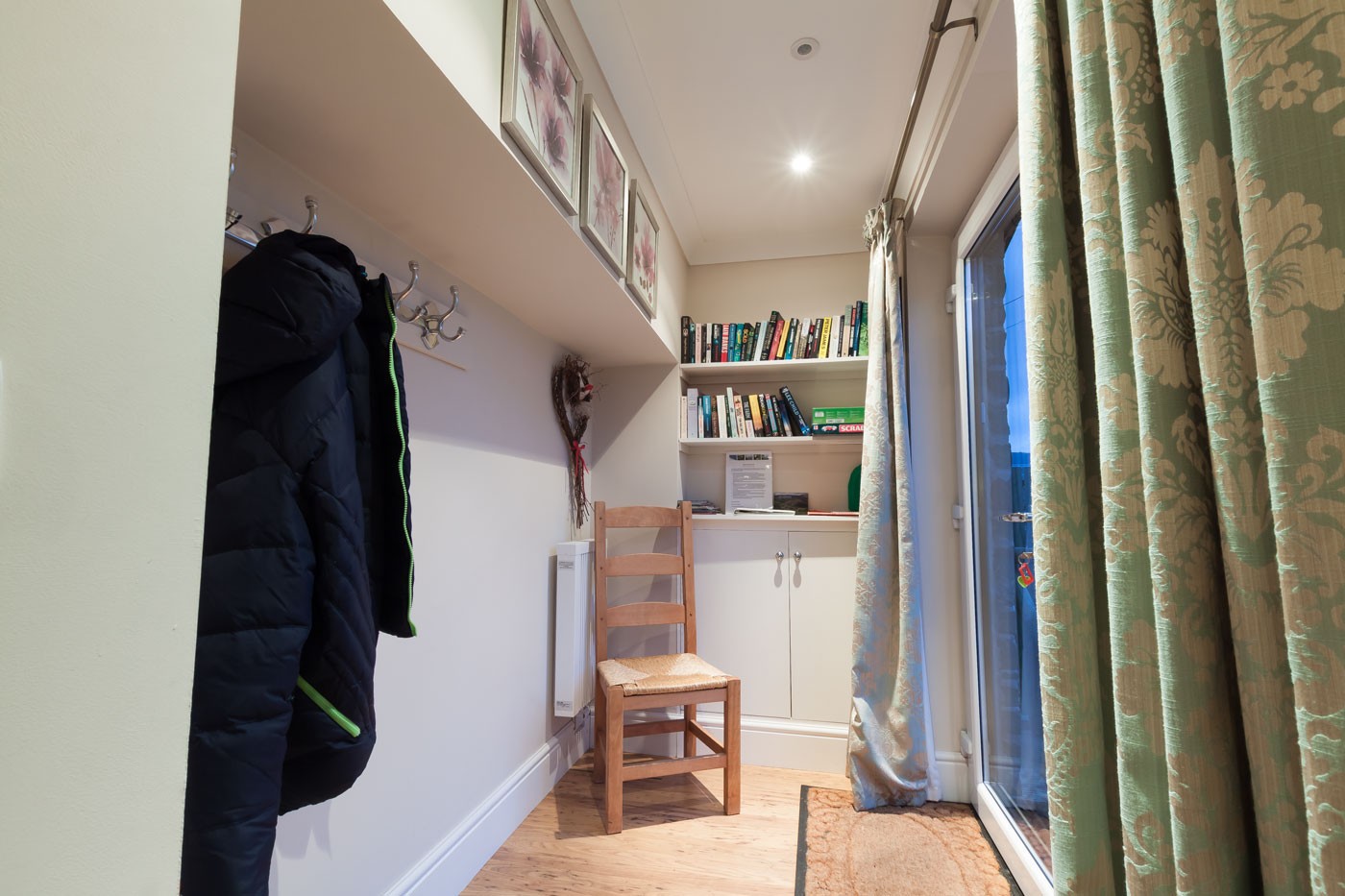 Hallway with chair, bookshelf and window.