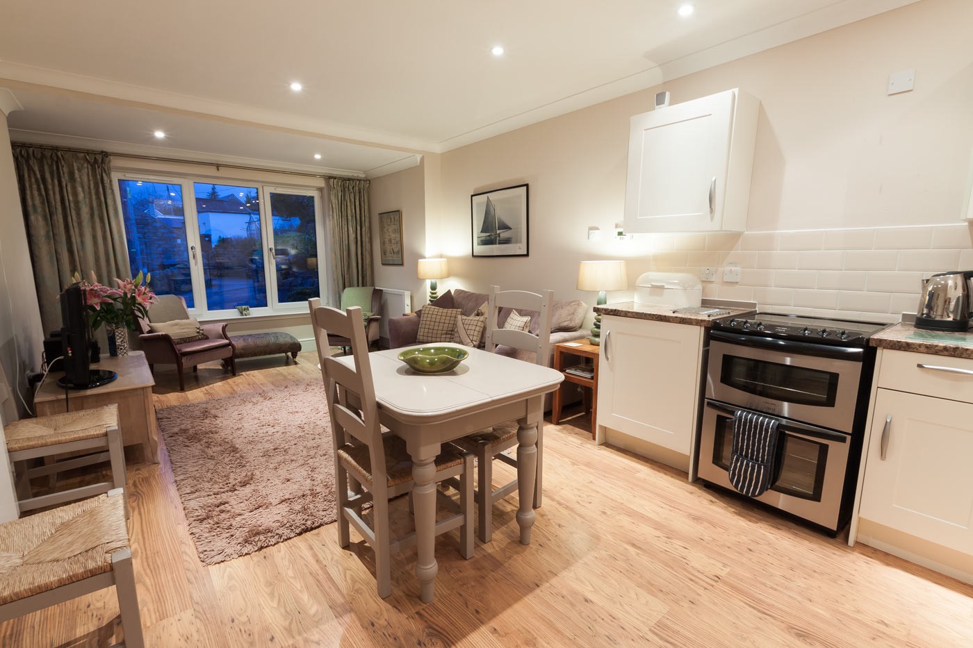 Kitchen with oven, dining room table and chairs and living room sofas.