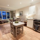 Kitchen with oven, dining room table and chairs and living room sofas.