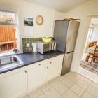 Kitchen with sink, microwave and fridge/ freezer leading to dining room.