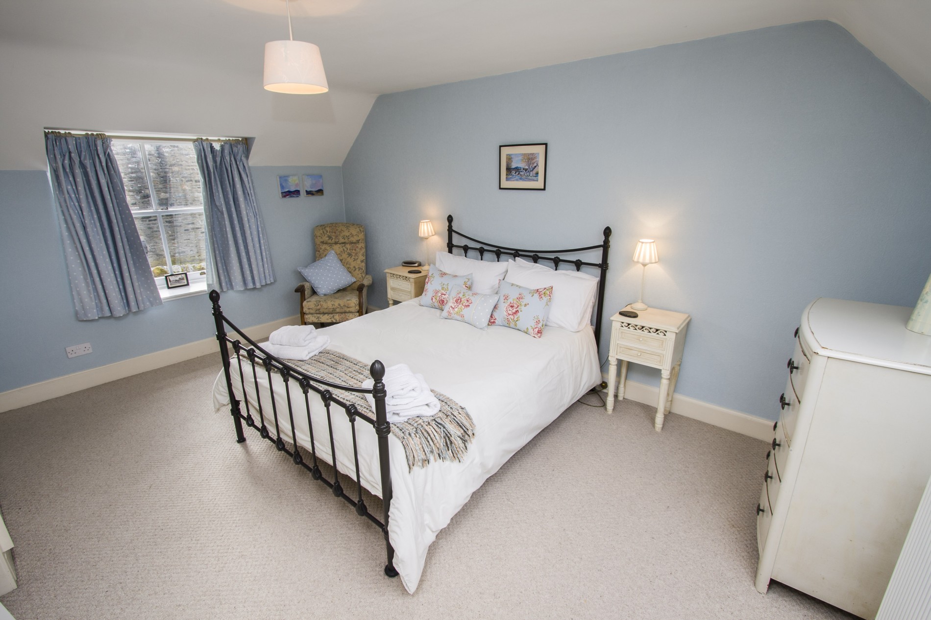 Double bedroom with armchair and window.