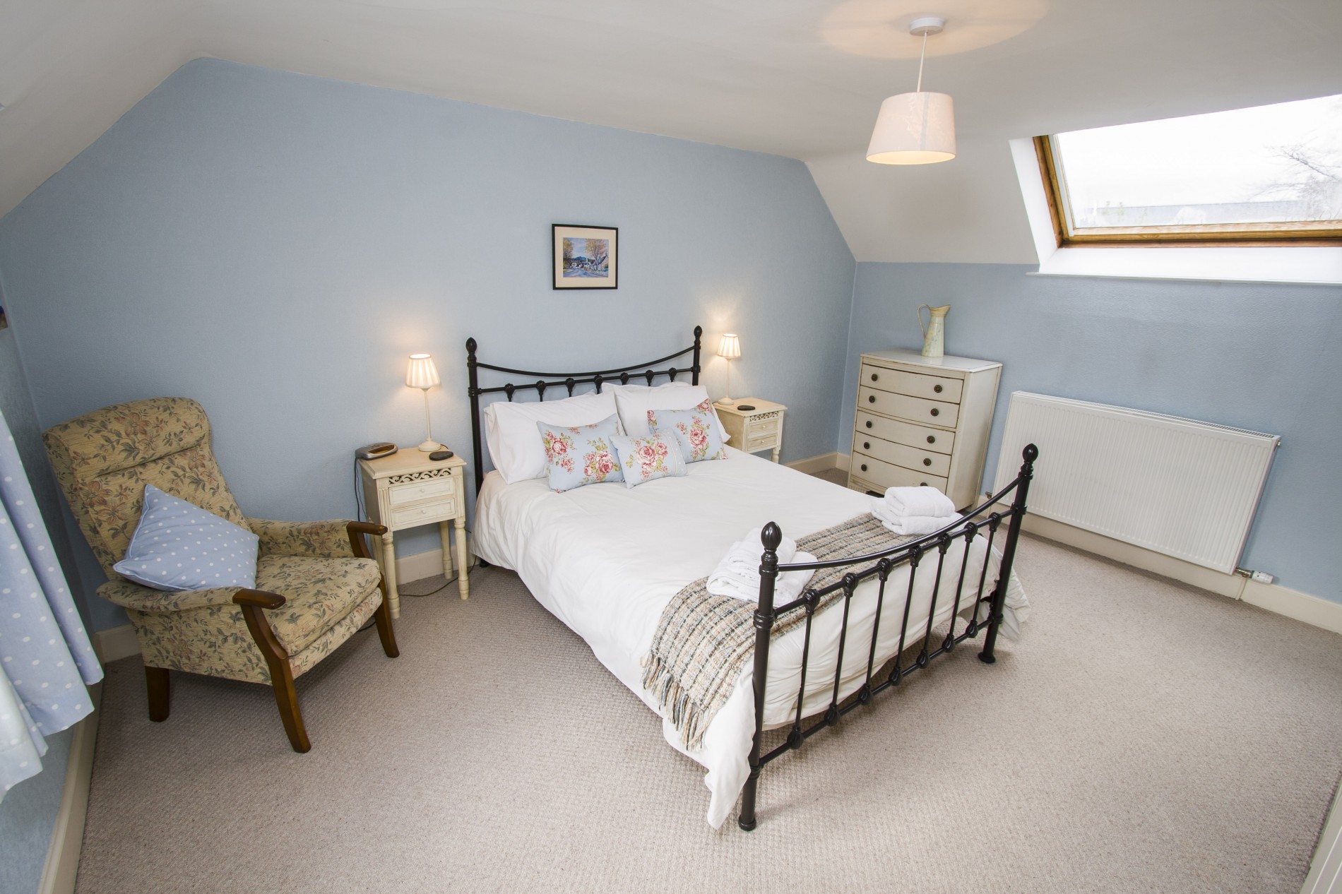 Double bedroom with armchair and chest of drawers.