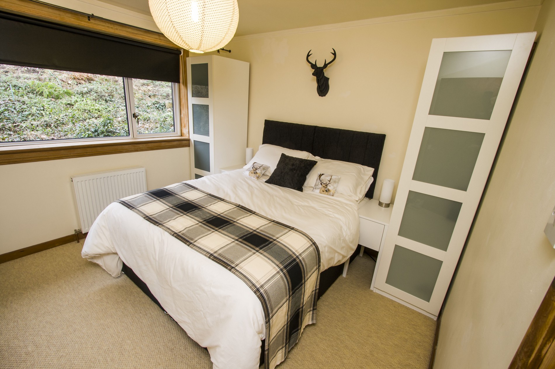 Double bed with two small wardrobes either side and a long window.