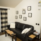 Living room with a black sofa and several pictures hanging on the wall.