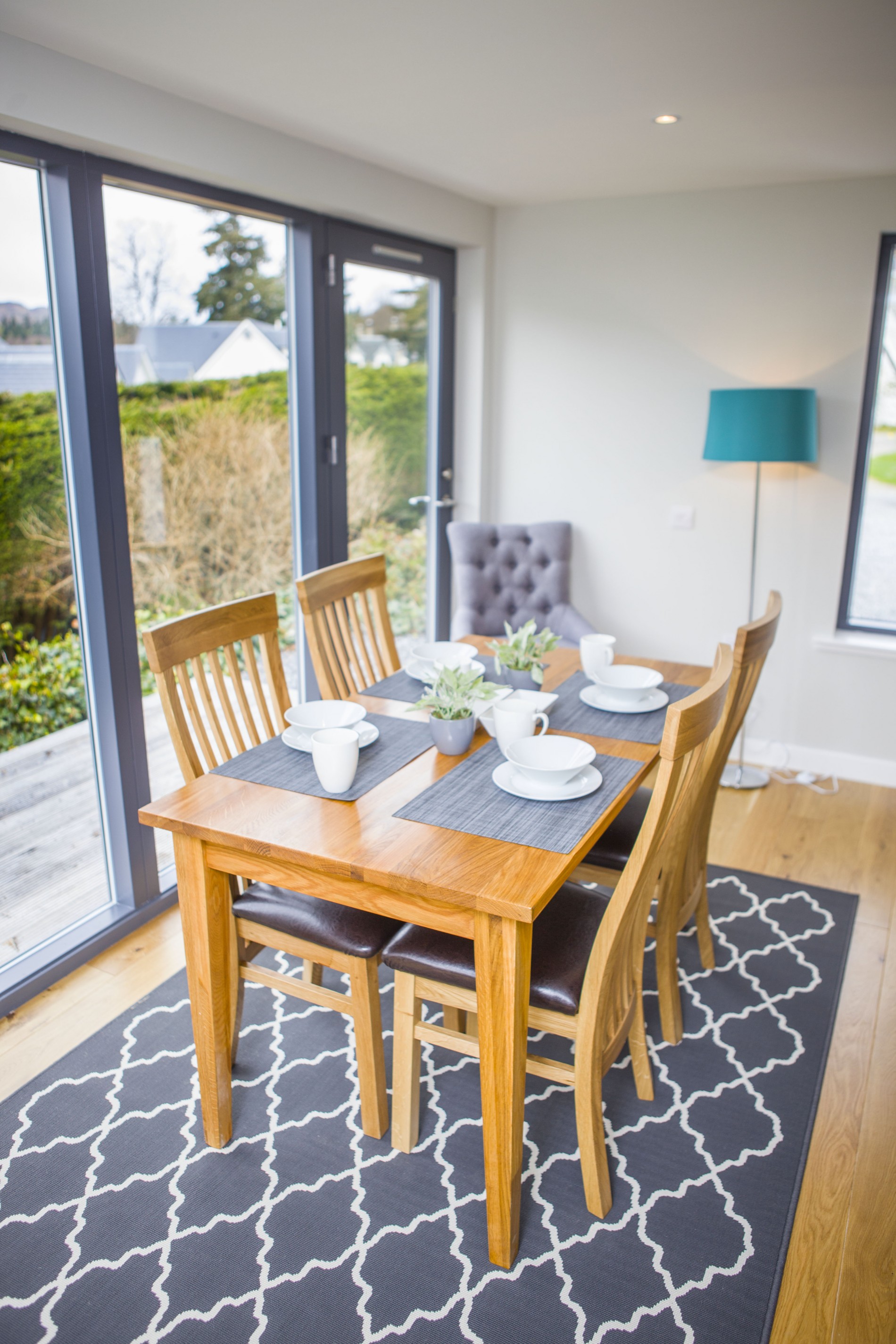 The dining table is situated next to the large Scandinavian windows and door which leads out to the decking area