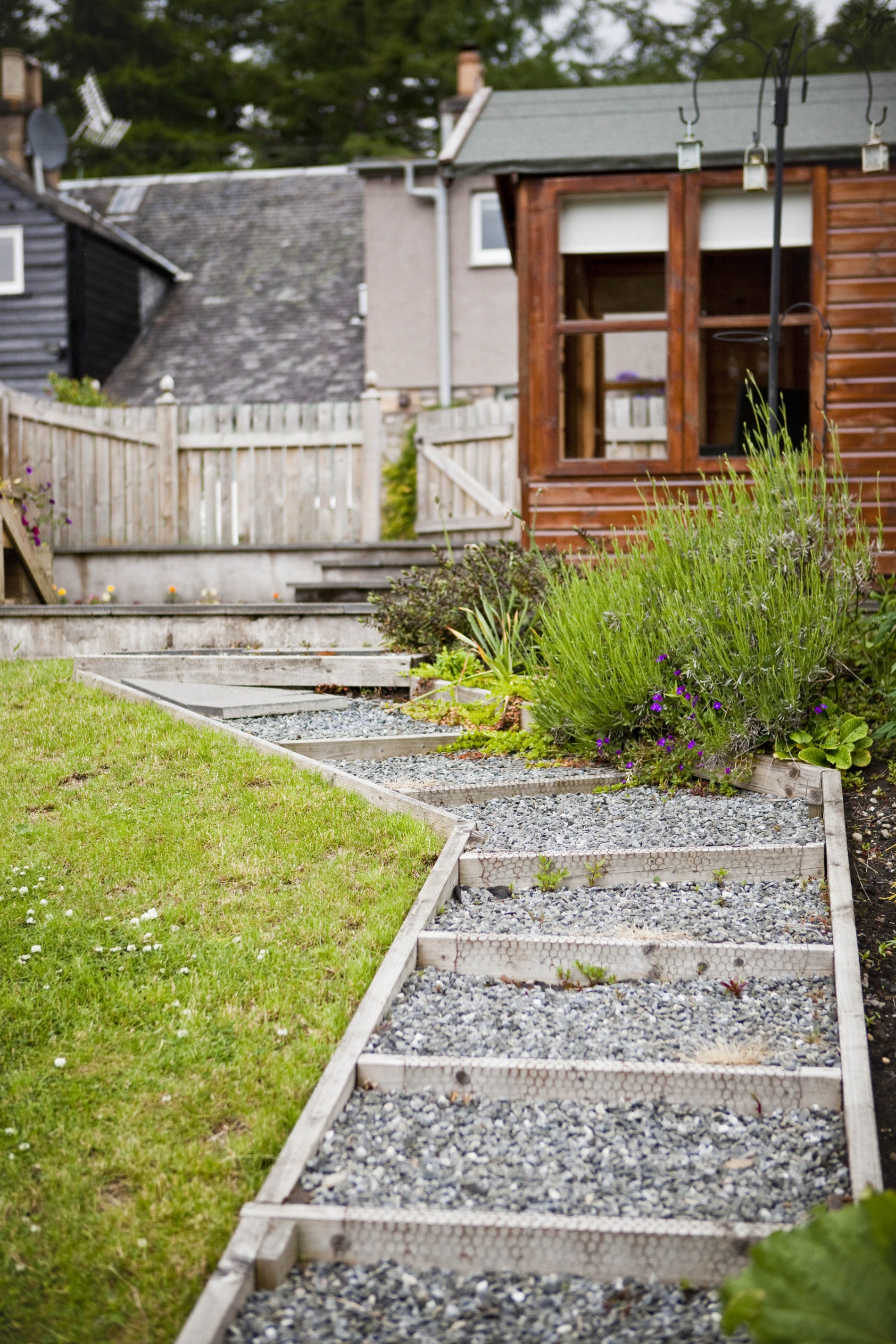 Steps beside the sloping lawn lead to the lower terrace of the garden where the games shed with dart board and table football can be found.