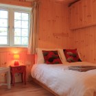 Wooden bedroom with a double bed, chair, bedside table and window