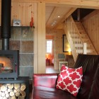 Living room with sofa and wood burner looking onto wooden staircase
