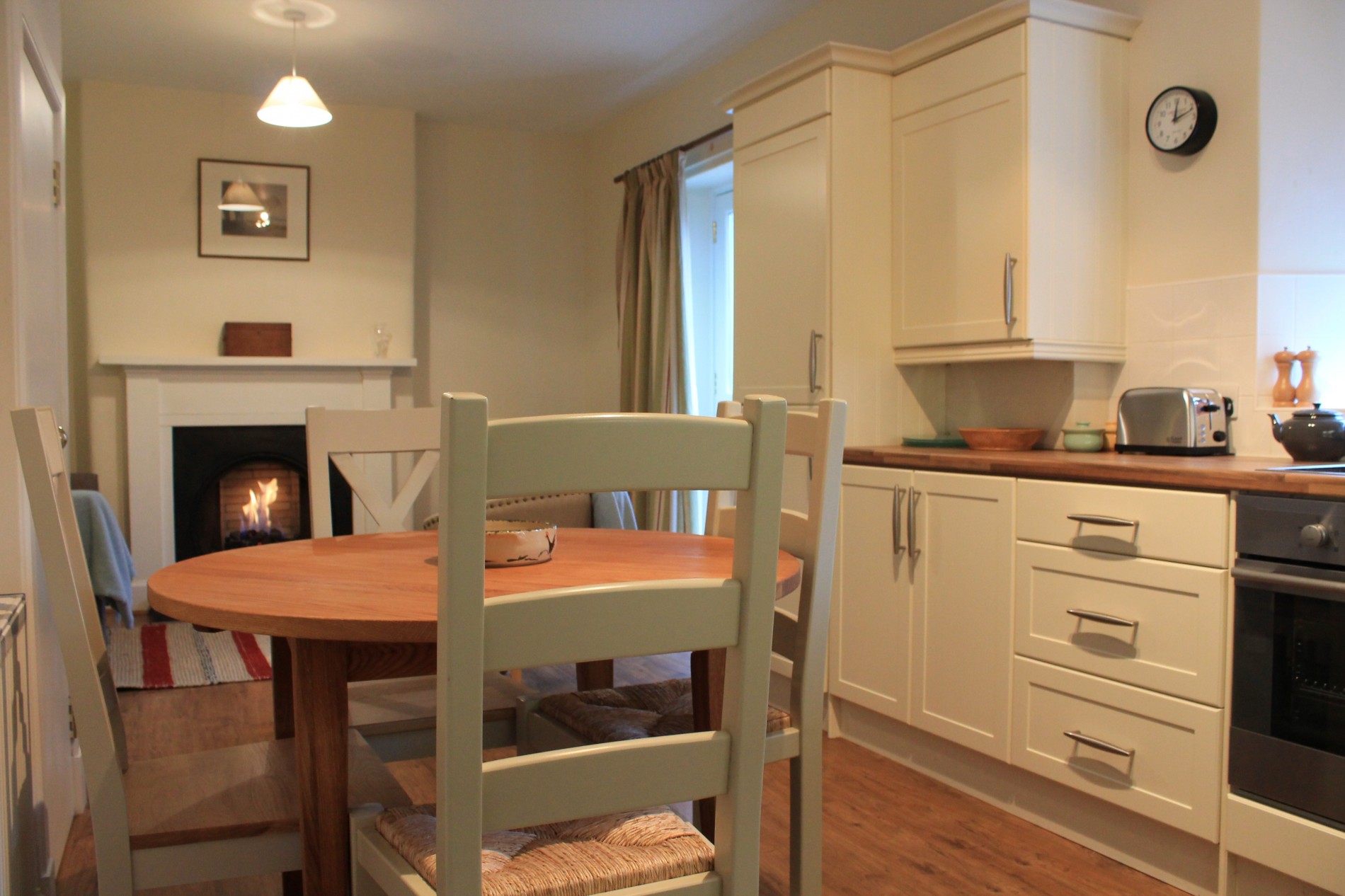Dining room/ kitchen with 4 person dining table, oven and fireplace in background
