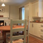 Dining room/ kitchen with 4 person dining table, oven and fireplace in background