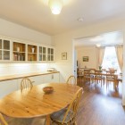 Small dining table in kitchen looking onto larger dining table in dining room